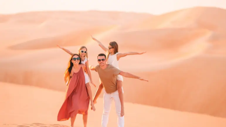 Family enjoying sightseeing in the desert dunes during sunset.