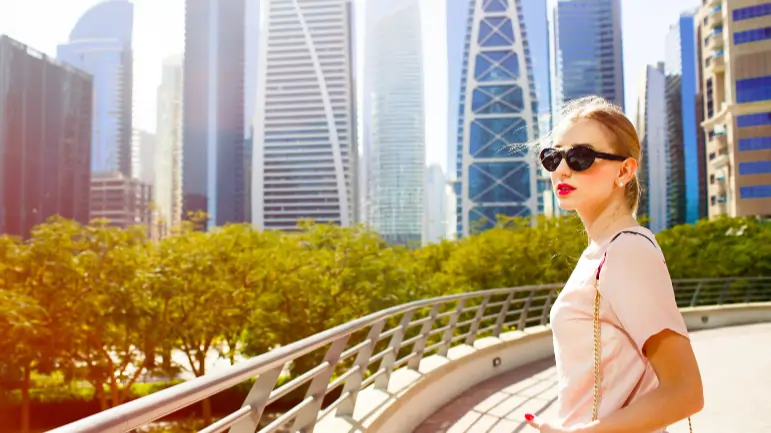 Woman enjoying urban sightseeing on a bridge with modern city skyscrapers in the background.