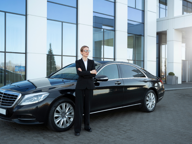 Luxury chauffeur service in Abu Dhabi with professional driver standing beside premium black sedan