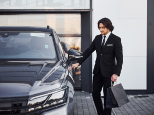 Private chauffeur opening car door for passenger beside luxury sedan in Abu Dhabi