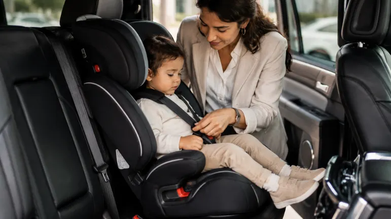 Parent securing a toddler in a properly installed child safety seat inside a luxury SUV for a safe airport pick up Abu Dhabi service.